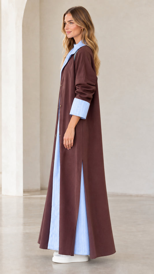 Side profile view of women's brown maxi duster coat featuring side slit and contrast hem detail