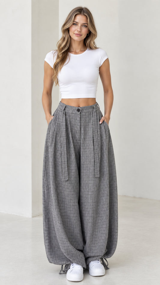 Front view of woman wearing grey micro-plaid pleated balloon pants with white crop top